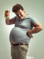 Image showing Obese, weight gain and beer for man in studio with alcohol for unhealthy habit, plus size and humor. Overweight person with glass in hand and fat stomach for cheers and comedy for comic expression