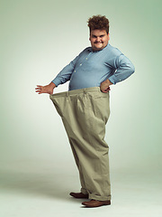 Image showing Happy man, portrait and plus size with weight loss or pants for measurement or waist on a studio background. Male person with smile for healthy diet, obesity or overweight in clothing on mockup space