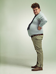 Image showing Business man, portrait and plus size with grumpy, joke and silly in a studio with arms on hips. Goofy, employee and office fashion with comedy and clothing with green background and funny humor