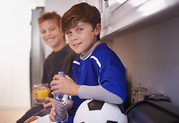 Image showing Children, portrait and soccer ball as friends in home with drink for sports training in kitchen for exercise, workout or juice. Male people, athlete and face in apartment with water, cardio or kit