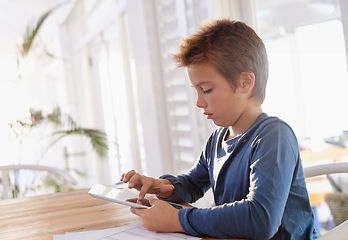 Image showing Child, tablet and notes in house for homework, elearning and games on table with internet and online. Young boy or kid with technology and finger on screen for touch, scroll or study for education