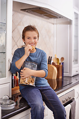 Image showing Portrait, smile and cookie jar with boy child in kitchen of home, eating biscuits on counter in morning. Breakfast, food and relax with happy young kid in apartment for hunger, snack or treats