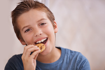 Image showing Portrait, smile and boy eating cookie in kitchen of home for hunger, sweet snack or treats. Face, food or biscuit with happy young teen kid biting baked goods alone in apartment for satisfaction