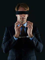Image showing Blindfold, businessman and handcuffs for corruption, fraud and white collar crime isolated on dark studio background. Male person, corporate worker and banker with scam, money laundering and bribery