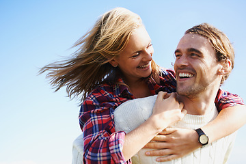 Image showing Happy couple, travel and bonding together in nature, piggyback and romantic getaway on holiday by blue sky. Man, woman and love on vacation on weekend break, joy and adventure in outdoor on honeymoon