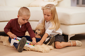 Image showing Children, puppy and toy in a home with animal, pet and youth development in a living room. Golden retriever, kids and fun with dog together by a couch in a house with bonding and sibling on the floor