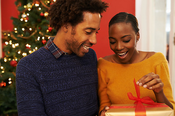 Image showing Christmas, present and black couple giving a box or opening surprise on festive holiday or vacation with happiness. Excited, woman and man offer a gift in home with love and kindness in marriage