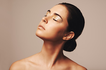 Image showing Woman, eyeshadow and gold glitter on eyes for beauty, cosmetology and glamour with cosmetics on beige background. Makeup, elegance and fashion model in studio, art or creativity with shimmer and glow