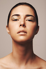 Image showing Woman, portrait and gold glitter on eyes for beauty, cosmetology and glamour with cosmetics on beige background. Eyeshadow, makeup and fashion model in studio, art or creativity with shimmer and glow