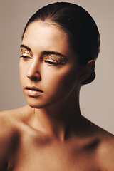 Image showing Gold glitter, beauty and woman with eyeshadow, makeup and cosmetology with shimmer for shine on beige background. Glamour, sparkle and fashion model in studio, cosmetics and elegance with creativity