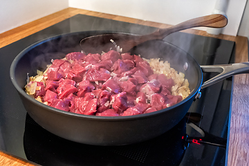 Image showing sliced onions and meat are frying in a pan