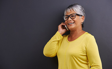 Image showing Glasses, phone call and senior woman in studio for communication, good news or gossip. Contact, mockup and elderly female person on mobile conversation with cellphone for talking by black background.