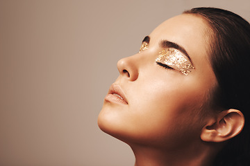 Image showing Woman, face and gold glitter on eyes for beauty, cosmetology and glamour with cosmetics on beige background. Eyeshadow, makeup and fashion model in studio, art or creativity with shimmer and glow