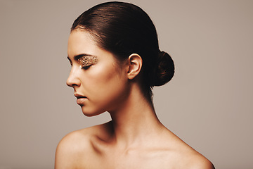 Image showing Woman, profile and gold glitter on eyes for beauty, cosmetology and glamour with cosmetics on beige background. Eyeshadow, makeup and fashion model in studio, art or creativity with shimmer and glow