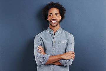 Image showing Portrait, smile and black man with arms crossed, fashion and afro on a blue studio background. Face, African person and model with casual outfit and stylish clothes with confidence and mockup space