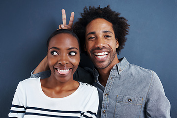 Image showing Happy, portrait and black couple with peace and love on studio background together with happiness. Crazy, face and sign for bunny ears in silly profile picture of people with casual fashion or style