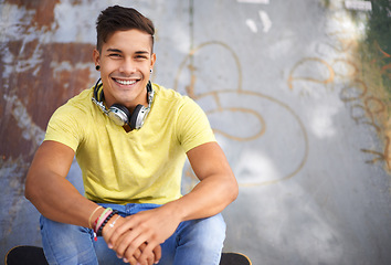 Image showing Gen z, portrait and young man at skatepark for skating practice or training for competition. Happy, smile and face of cool male person sitting on ramp with positive, good and confident attitude.