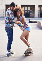 Image showing Happy, teaching and man with woman on skateboard in city on romantic and fun date together. Smile, couple and African female person learning skating with boyfriend skater in urban town with love.