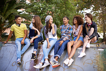 Image showing Conversation, happy and group of friends at skatepark in city for bonding, talking and sitting together. Smile, diversity and young teenagers in conversation with skateboard in town for practice.