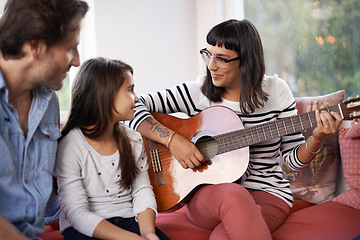 Image showing Mother, music and playing guitar for family at home, relaxing and enjoying together on couch. Performance, father and child with woman in living room, entertainment and happy with musical instrument