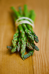 Image showing Asparagus, closeup and counter for nutrition, wellness or organic diet on wood countertop. Vegetable, health or produce for eating, gourmet and meal or cuisine with vitamins or fibre for weight loss