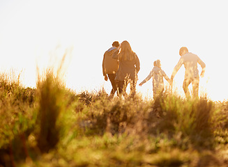 Image showing Family, nature and walk at sunset, bonding and exercise for parents and children. Lens flare, autumn and grass for hike on holiday in English countryside, mother and father for outdoor activity