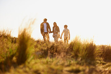 Image showing Family, grass and walk at sunset, nature and bonding with exercise for parents and children. Lens flare, autumn and hike on holiday in English countryside, mother and father for outdoor activity