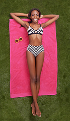 Image showing Happy woman, portrait and lying with towel on green grass above for relaxation or outdoor summer holiday. Top view of young female person with smile in relax, bikini or fashion on field in nature