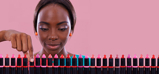 Image showing Lipstick, makeup and choice of color with black woman in studio isolated on pink background for cosmetics. Face, retail and shopping for beauty product with young customer on space for decision