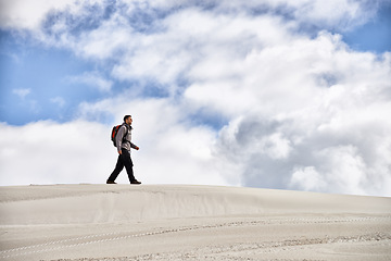 Image showing Hike, dunes and male in nature for adventure, walk and desert landscape for travel or exercise. Fitness, holiday and nomad man person in Sahara terrain, outdoor or freedom in dry climate and scenery