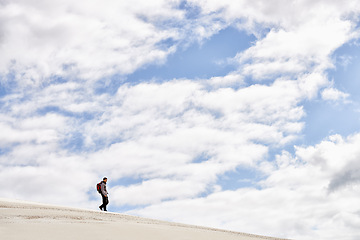 Image showing Hike, dunes and sky with male person in nature for adventure, walk and desert landscape with clouds. Fitness, travel and nomad man people in Sahara, outdoor and hiking in dry climate and scenery