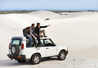Image showing Friends, people on car in desert and travel for tourism in Dubai for safari, road trip and view. Adventure, journey and transportation with offroad vehicle or 4x4 on vacation for break outdoor