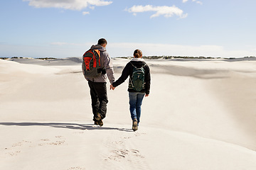 Image showing Backpack, travel or couple in desert holding hands for adventure, journey or resort, location or explore. Freedom, love or back of people in Egypt for sand dunes walking, wellness or hiking in nature