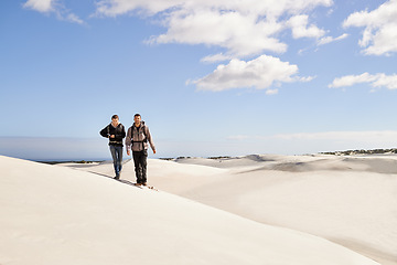 Image showing Couple, hiking and sand outdoor or desert with dune, sky and clouds for walking, climbing and move for recreation. Man, woman and young for adventure in weather and dry for season and destination