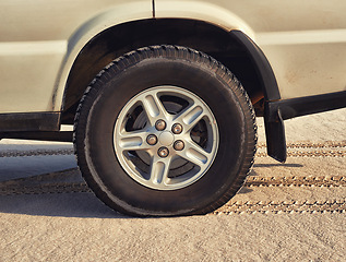 Image showing Tyre, car in desert and travel with transport outdoor, off road vehicle for sand dunes and journey on vacation. Wheel, 4x4 and SUV with adventure, exploration and destination for tourism in Dubai