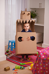 Image showing Child, box and play for robot and imagination in bedroom for fun and recreation in home on weekend. Young kid, toddler and innocent with costume for development and cute for toy and childhood