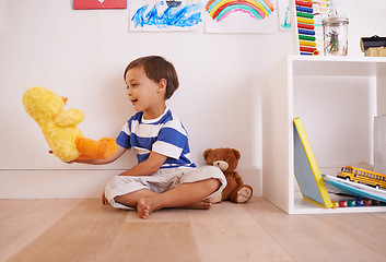 Image showing Child, toy and play with teddy, smile and happiness for fun and joy at home or daycare. Boy, cute and positive with stuffed animal, laugh and childcare for growth and cheerful on wood floor in house