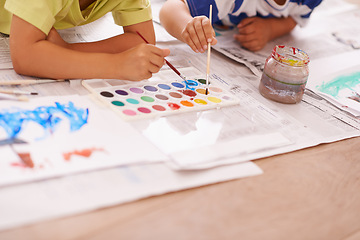 Image showing Children hands, palette and creative with paint brush on floor or playing, hobby and drawing together at home. Kids, motor skills and growth for childhood development with creativity for artwork