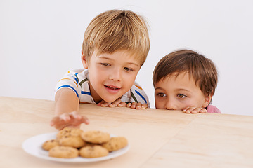 Image showing Children, boys and smile for cookies in home with stealing, peeking and childhood fun in at dining room table. Siblings, kids and happy for biscuits, snack and baked goods in kitchen of apartment