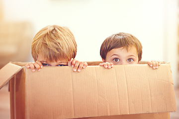 Image showing Children, box and eyes of siblings playing in a house with fun, bonding and hide and seek games. Cardboard, learning and curious kid brothers in a living room with fantasy, imagine or hiding at home