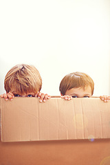 Image showing Box, kids and eyes of siblings playing in a house with fun, bonding and hide and seek games. Cardboard, learning and curious boy children in a living room with fantasy, imagine or hiding at home