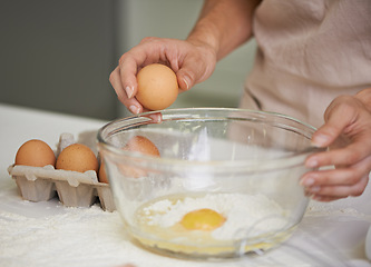 Image showing Hands, person and eggs with bowl, kitchen and flour for baking with whisk. Baker, muffin and food with countertop, apron and mixing for recipe preparation and recreation or hobby at home or house