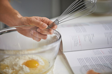Image showing Hands, person and whisk with bowl, kitchen and cookbook for baking. Baker, muffin or food with countertop, eggs and flour for recipe preparation and recreation or hobby at home or house with utensils