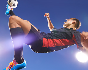 Image showing Football player, jump and kick with man and soccer ball, energy and challenge with skill in professional sport. Sky background, light and playing game at arena or stadium, action and exercise outdoor