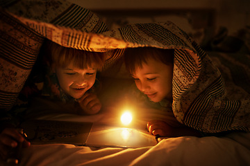 Image showing Blanket, flashlight and children at night with happiness reading a book with fantasy and magic. Friends, relax and storytelling in dark with light under duvet at sleepover with a pillow tent