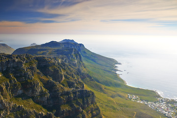 Image showing Mountain, island and cloudy sky at ocean cliff with natural landscape, hill and beach at travel location. Nature, city and sustainable environment with earth, sea and sunset at holiday destination