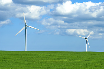 Image showing Wind turbine, grass and sky with clouds for nature in environment and outdoor for landscape and energy. Sustainability, weather and season with ecology for farm and field in agriculture and industry