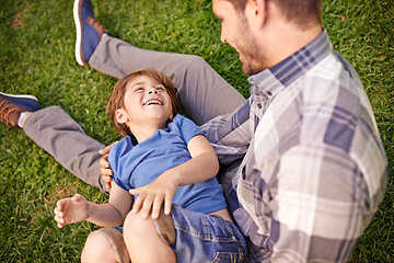 Image showing Family, man and child on grass in garden, park or outdoors for talking, bonding and playing together. Young boy and smiling with dad on lap for innocent jokes and fun while laughing for happiness