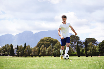 Image showing Man, soccer player and dribble with ball on field for moving, speed or skills in low angle at club on training ground. Person, football and sport with exercise, steps and workout for fitness in game