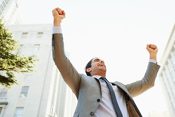 Image showing Smile, success and hands raised with businessman in city for celebration of bonus or promotion. Corporate, building and sky with happy employee cheering outdoor in urban town for target or goals